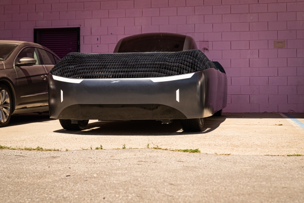 In this image, the Alef Model A is pictured outdoors, showcasing its distinctive and futuristic design in a real-world setting. The car's sleek, wingless body, characteristic of Alef Aeronautics' vision for urban air mobility, is on full display. The front of the vehicle features minimalist lighting elements, enhancing its modern aesthetic
